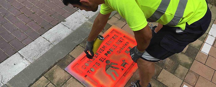Un membre de la brigada municipal pinta un dels cartells al terra de l'avinguda Lluís Companys.
